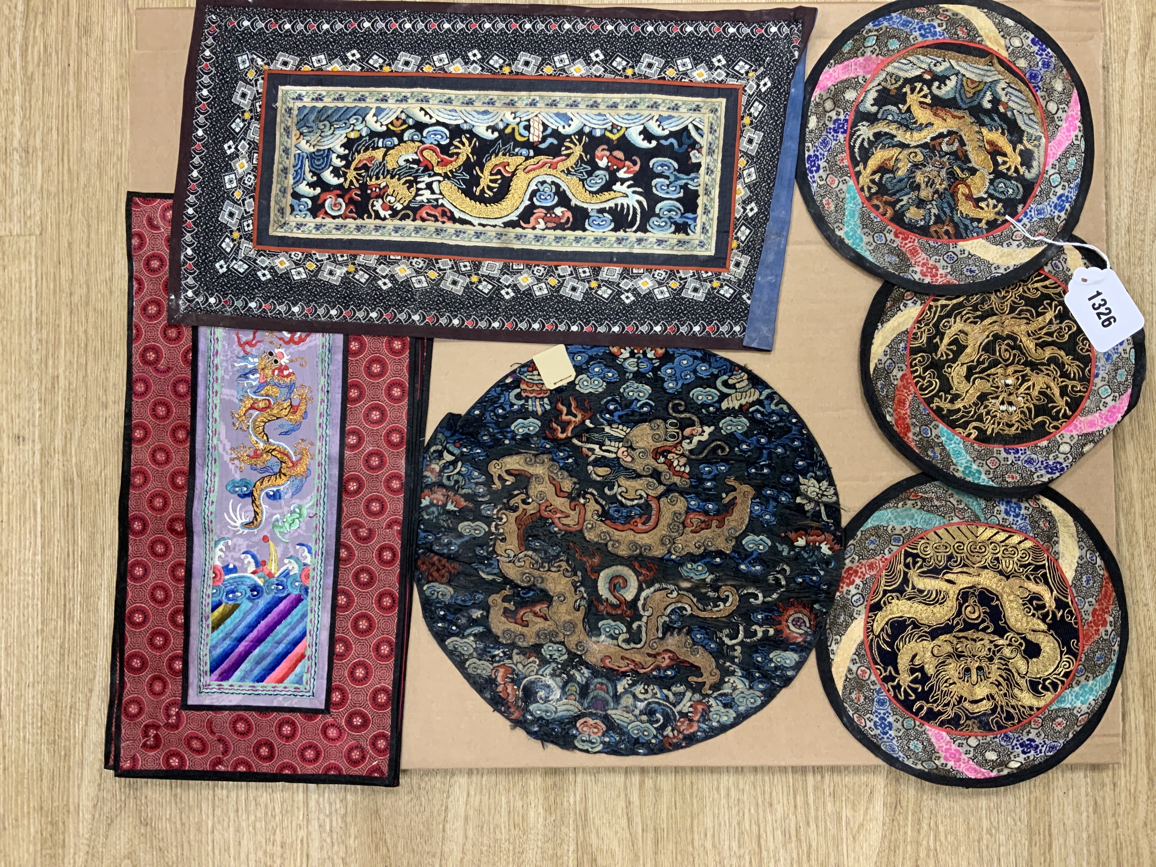 A group of five Chinese gold thread and polychrome silk embroidered circular mats, embroidered with central gold thread dragons four bordered in silk brocade, together with a set of four rectangular similar embroidered g